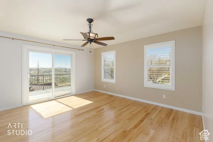 Hardwood flooring, sliding glass door with deck access, two windows with plantation shutters, and a ceiling fan with integrated lighting