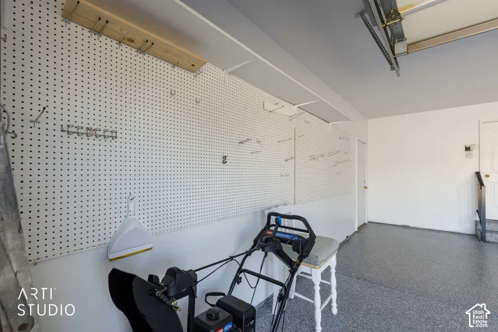 Garage with a speckled epoxy-coated floor, extensive pegboard wall storage, and overhead shelving