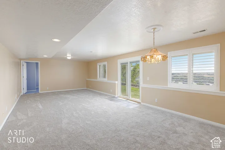 Recessed lighting, chandelier, sliding glass door, plantation shutters, and light-toned carpeting