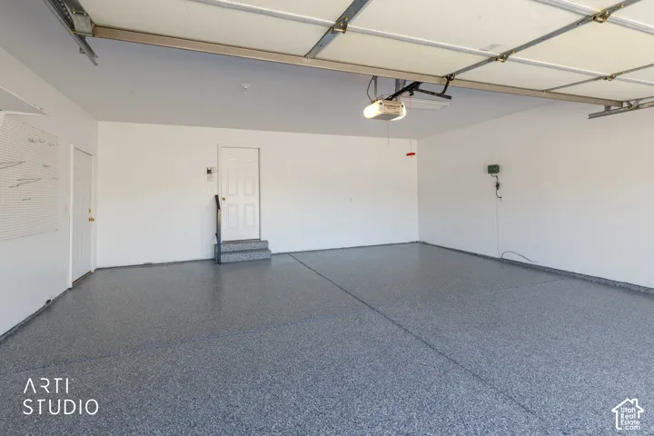Spacious garage featuring a durable speckled epoxy floor, white painted walls, and an automatic garage door opener