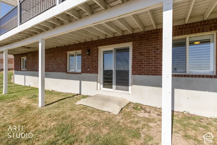 Brick exterior with white trim, patio door, white-framed windows, and covered outdoor space