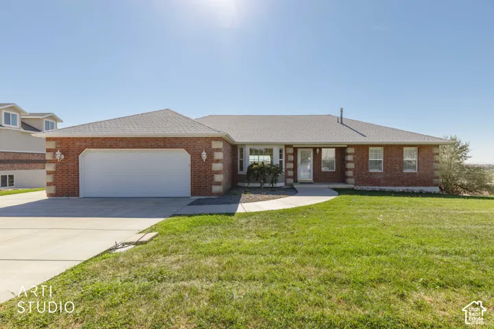 Brick exterior, attached garage, concrete driveway, front lawn, and mature landscaping