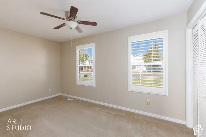 Recessed lighting, wood-finish ceiling fan, two windows with white plantation shutters, neutral-toned walls, and carpet flooring