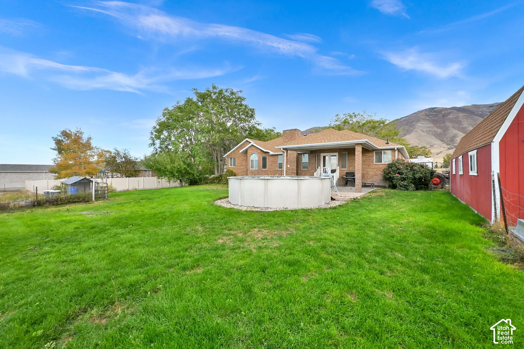 Spacious backyard with a large lawn, above-ground pool, and a red storage barn.
