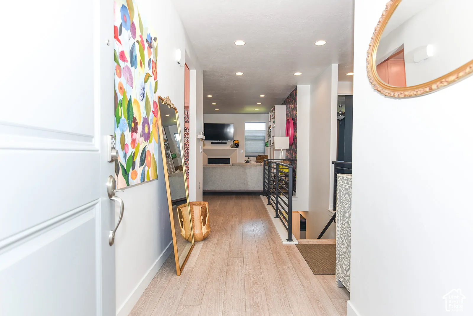 Light wood-finish flooring, recessed lighting, and a black metal railing