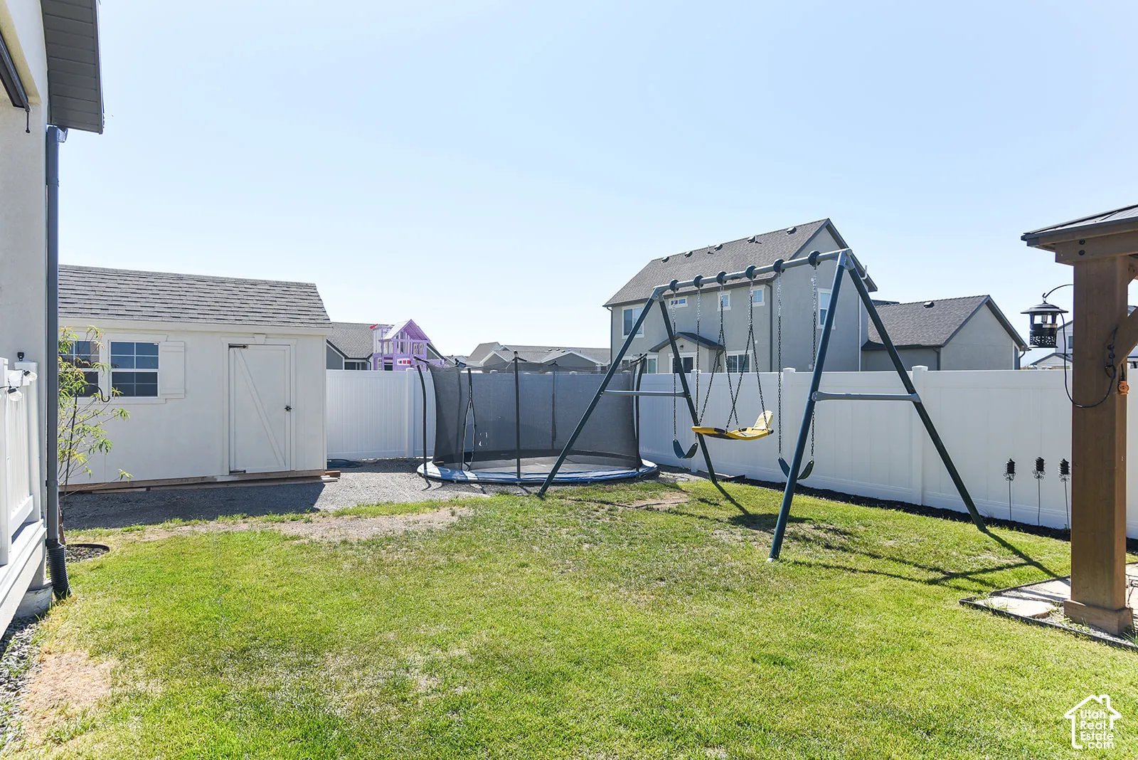 Expansive backyard featuring a white storage shed with a shingle roof, a privacy fence, and a grass lawn