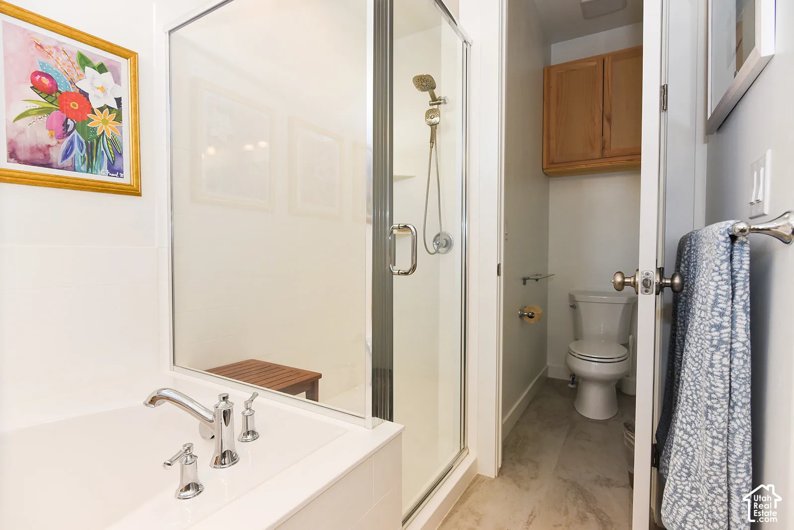 Enclosed shower with glass door, separate soaking tub with chrome fixtures, and a private water closet with wood-finish cabinetry