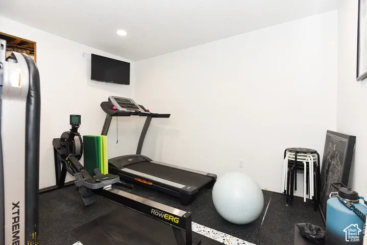 Recessed lighting illuminates this room featuring white walls and a wall-mounted display