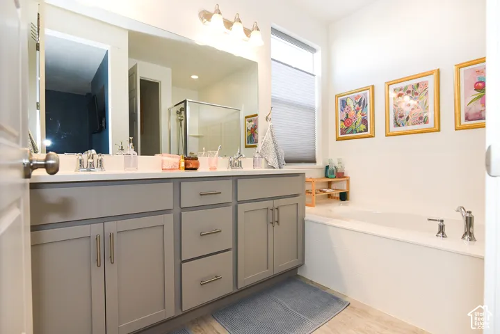 Dual vanity with light gray cabinetry, built-in bathtub, and a separate shower enclosure