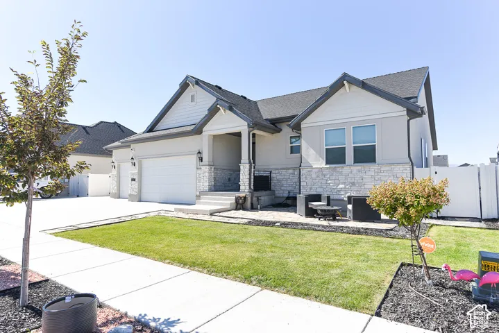 Contemporary home with a stone and stucco exterior, a dark shingle roof, an attached two-car garage, and a concrete driveway