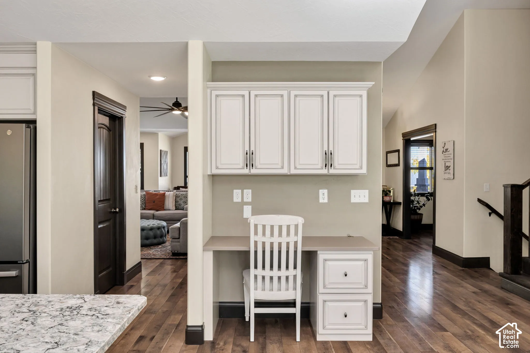 Built-in desk with overhead cabinetry, wood-finish flooring, and a stainless steel refrigerator