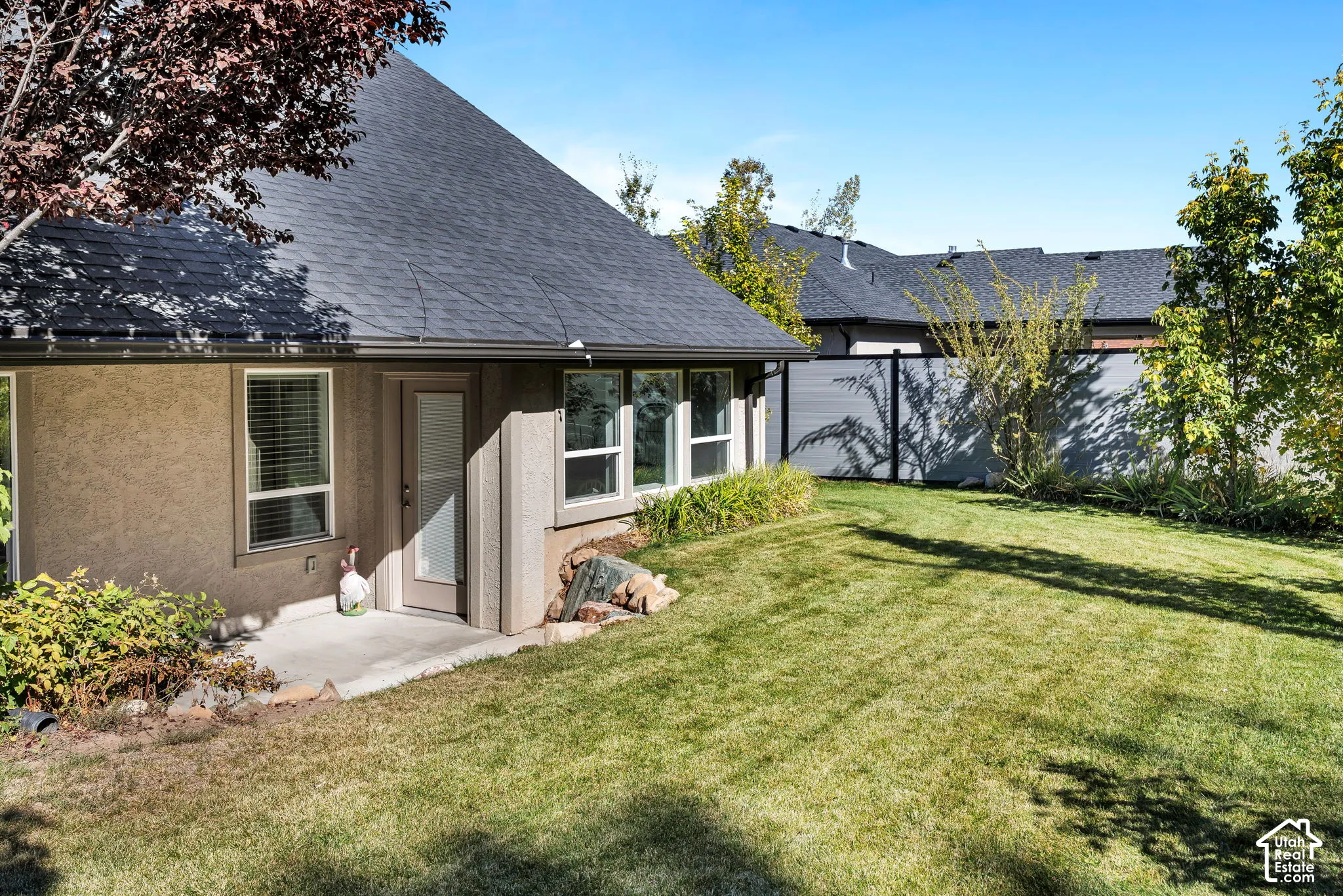 Expansive backyard featuring a manicured lawn, established trees, and a privacy fence