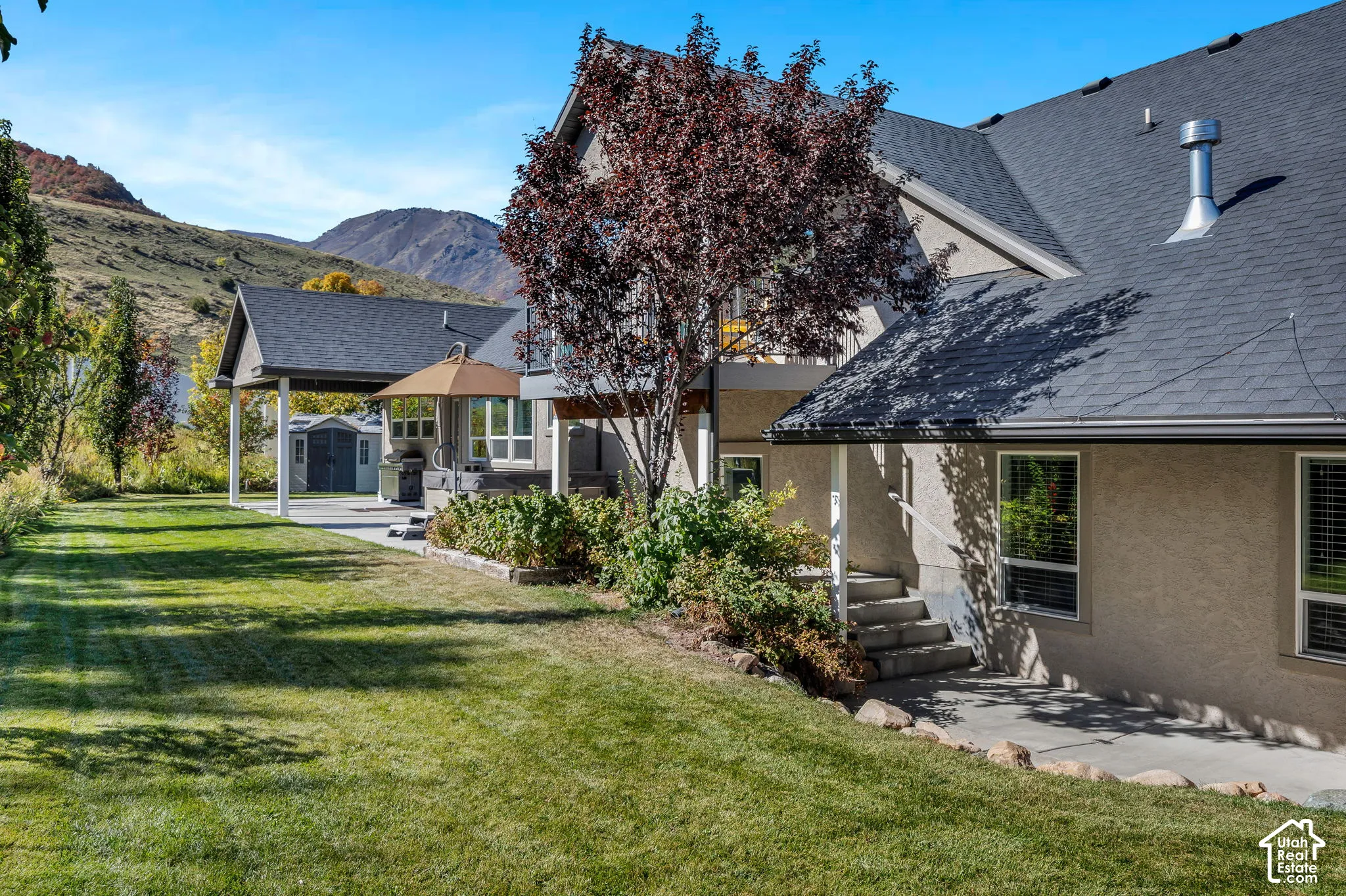Expansive grassy yard with mature landscaping, a covered patio, and a separate paved patio area