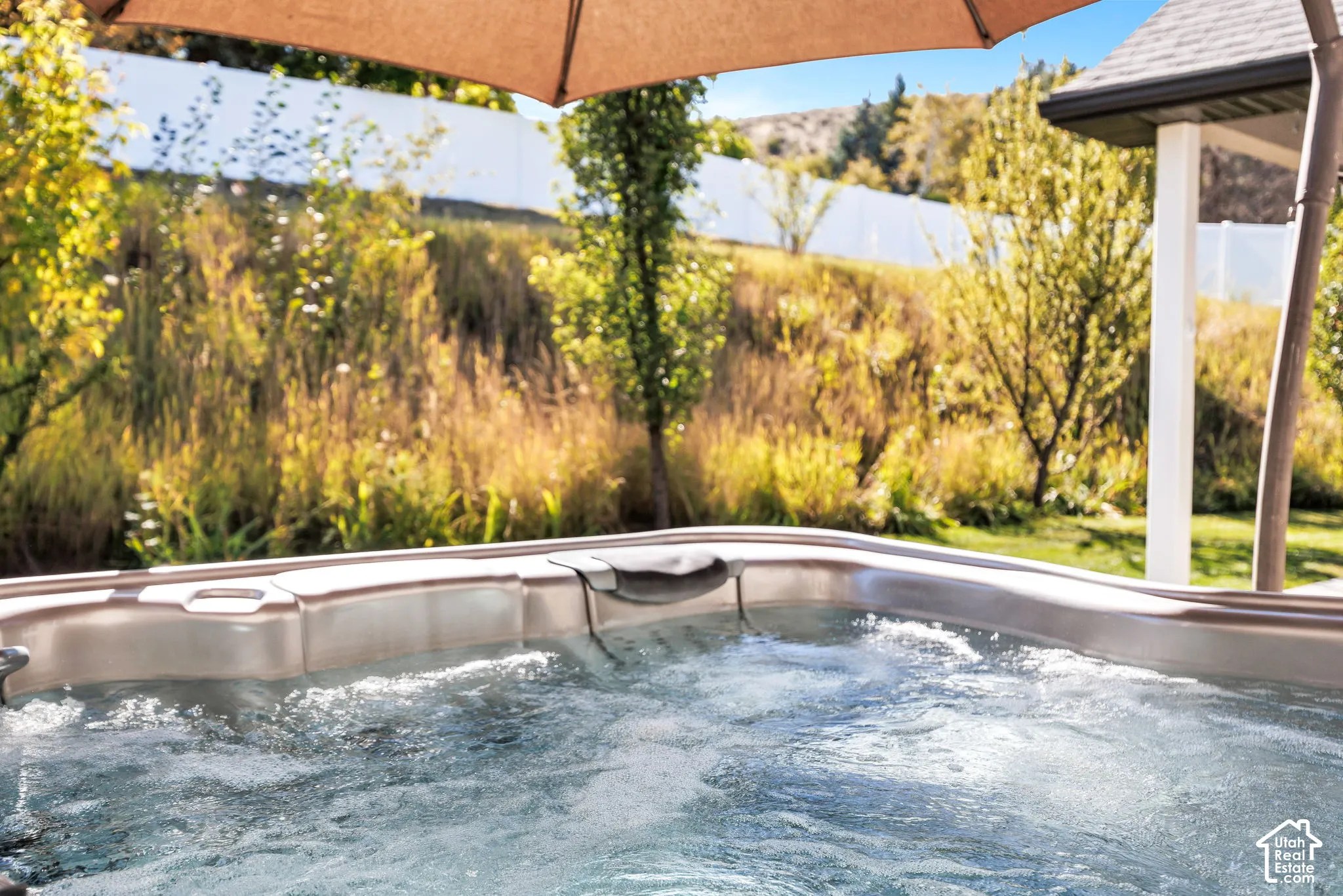 Heated outdoor spa with bubbling water, shaded by a cantilever umbrella