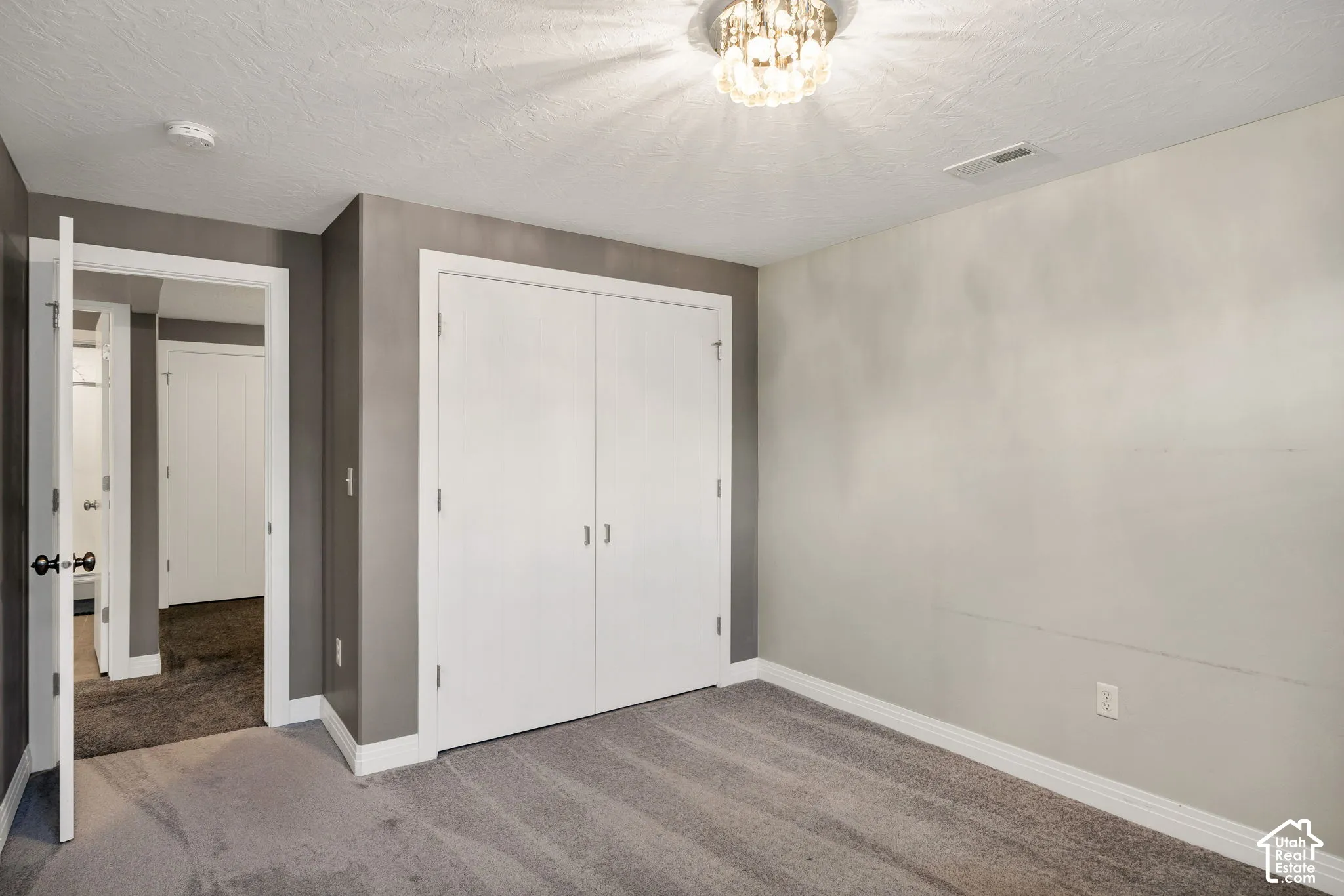 Recessed ceiling light fixture, neutral carpeting, and white bi-fold closet doors