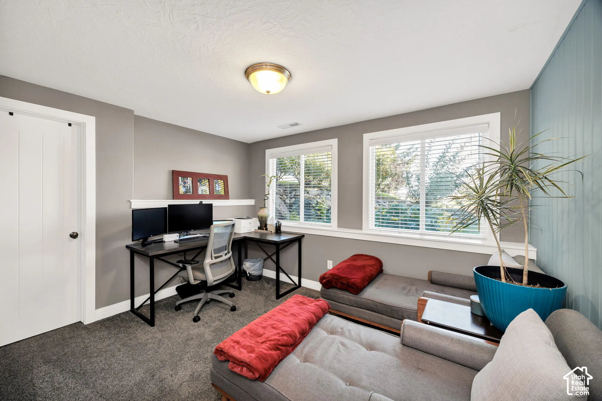 Recessed ceiling light fixture, two windows with blinds, built-in wall shelf, light gray wall paint, and textured ceiling
