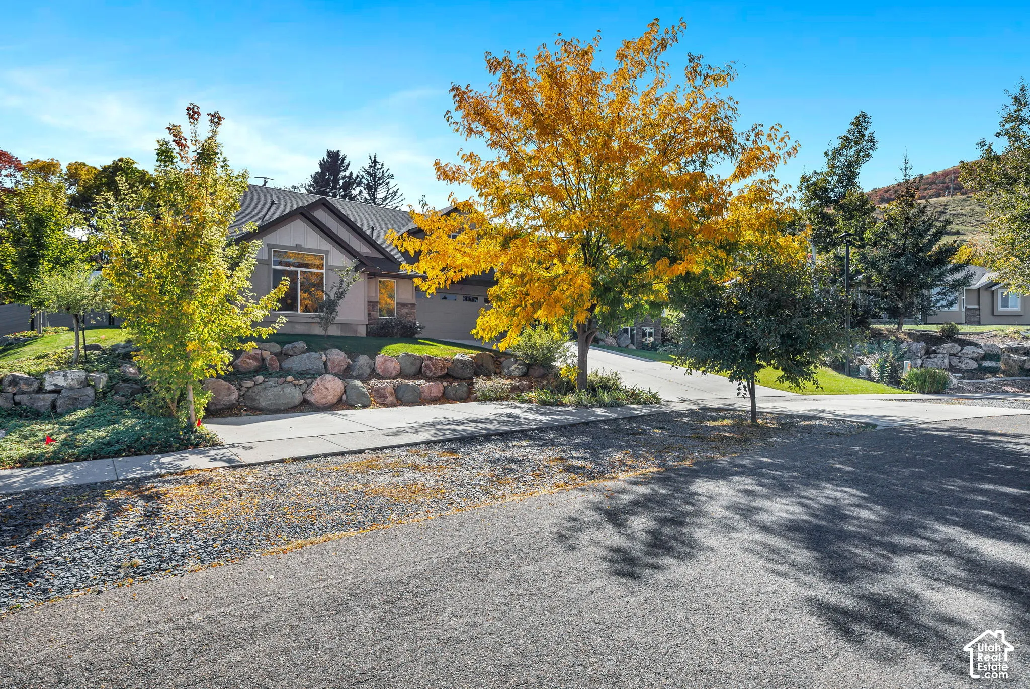 Single-story residence featuring a stone-faced retaining wall and a sloped, landscaped yard