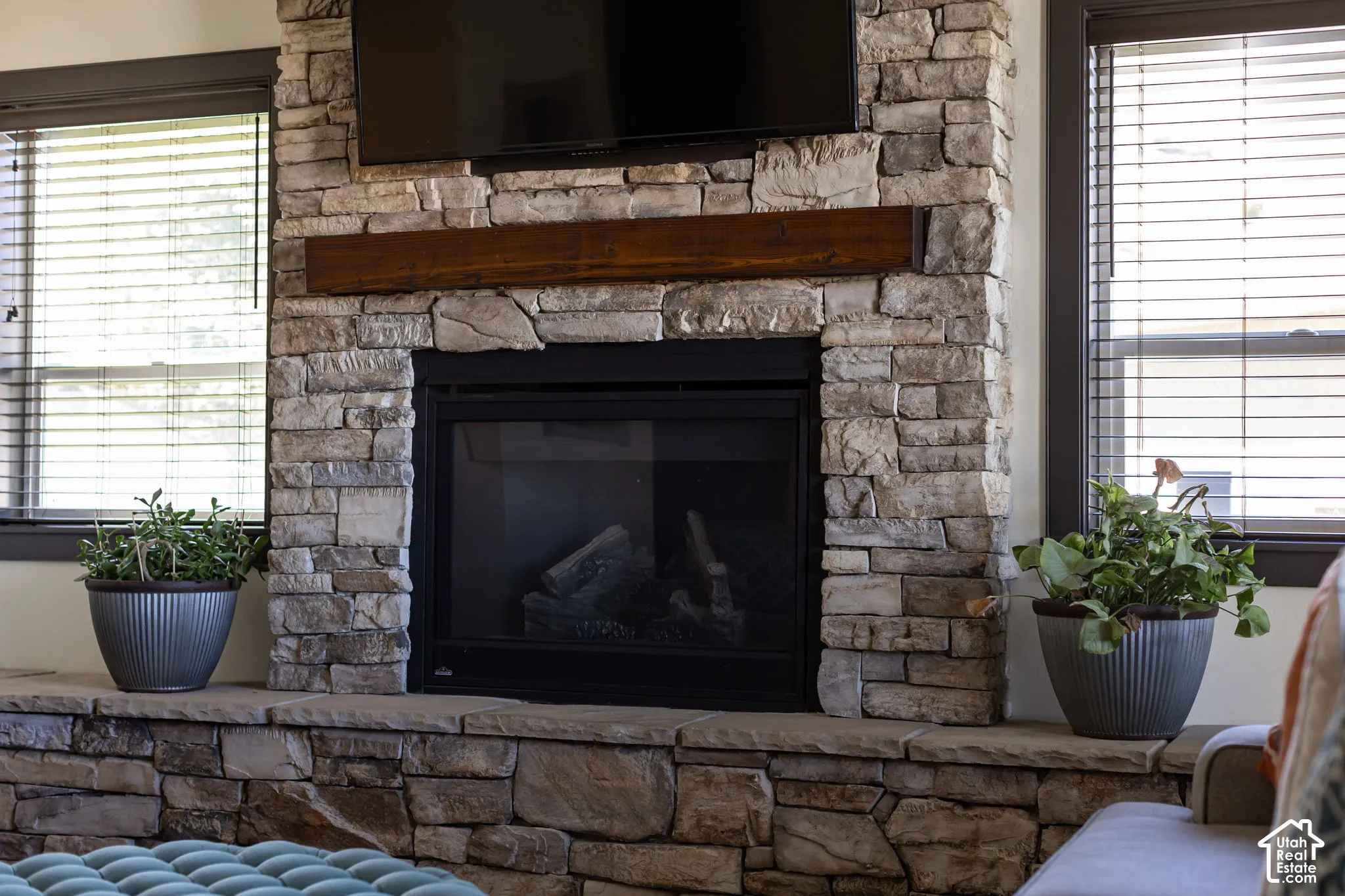 Stone-clad fireplace featuring a dark wood mantel and a built-in firebox with glass doors