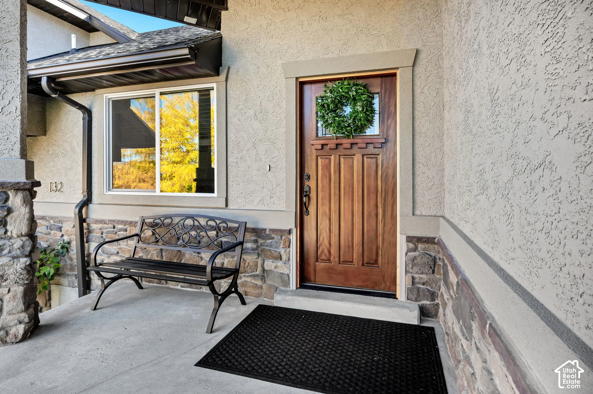 Stucco exterior featuring stone accents, a wood-paneled front door with decorative glass, and a large window