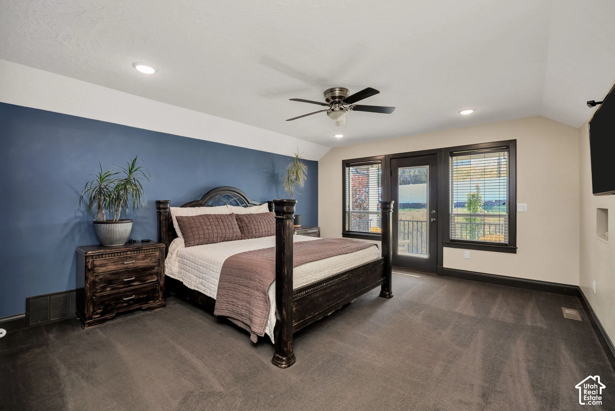 Recessed lighting, ceiling fan, carpet flooring, a dark accent wall, and exterior access via a glass-paneled door