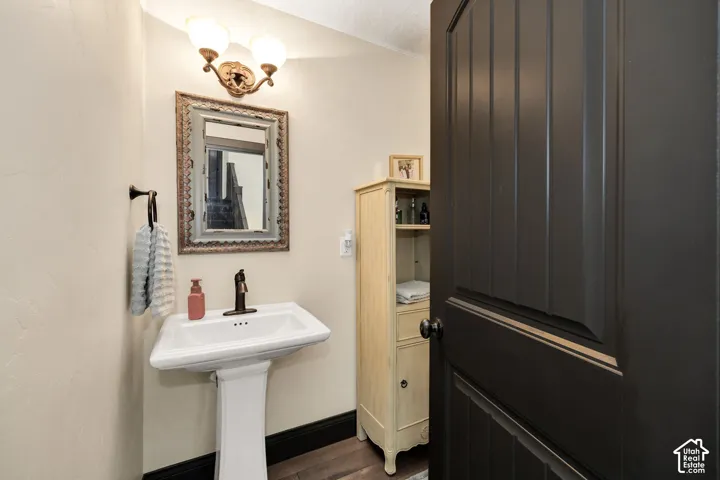 White pedestal sink with a bronze-finish faucet, framed mirror, and two-light vanity fixture