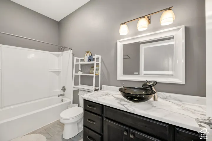 Bathroom featuring a white framed mirror, three-light vanity fixture, dark wood-finish vanity with a vessel sink, and a white tub/shower combination