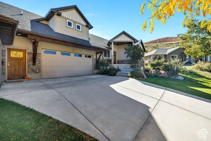 Stucco and stone facade with a multi-car driveway, attached garage, and covered entry