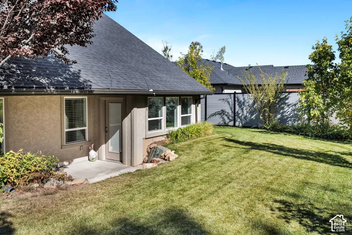 Expansive backyard featuring a manicured lawn, established trees, and a privacy fence