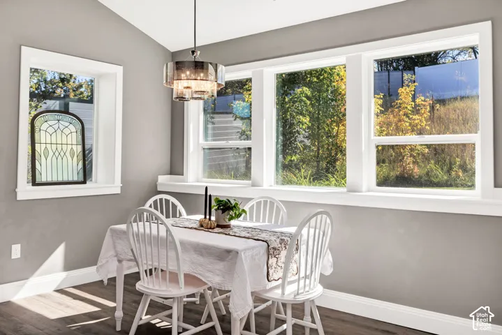 Wood-finish flooring with crisp white trim, multiple large windows, and a decorative pendant light fixture