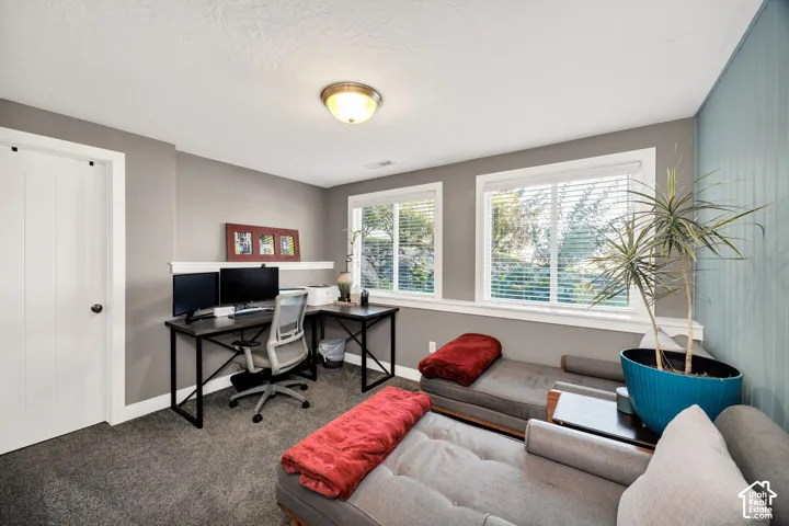 Recessed ceiling light fixture, two windows with blinds, built-in wall shelf, light gray wall paint, and textured ceiling