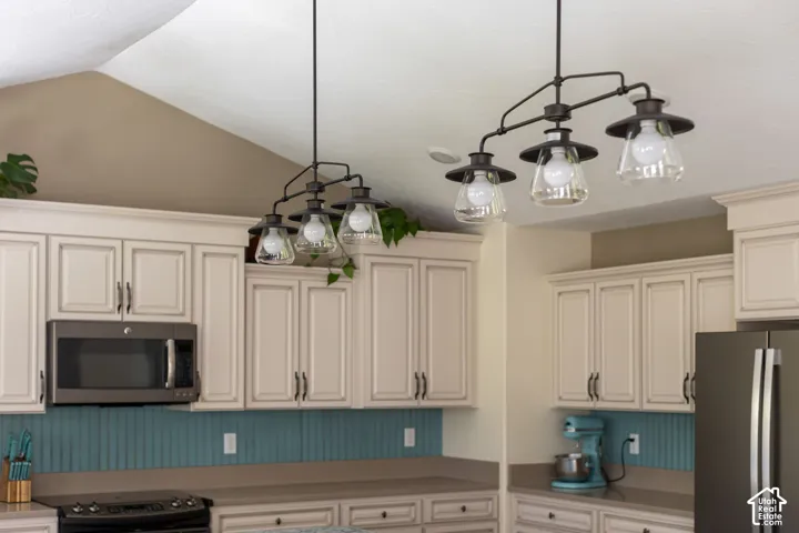 Vaulted ceiling, multi-light linear chandelier, extensive cabinetry with crown molding, beadboard backsplash, and built-in microwave