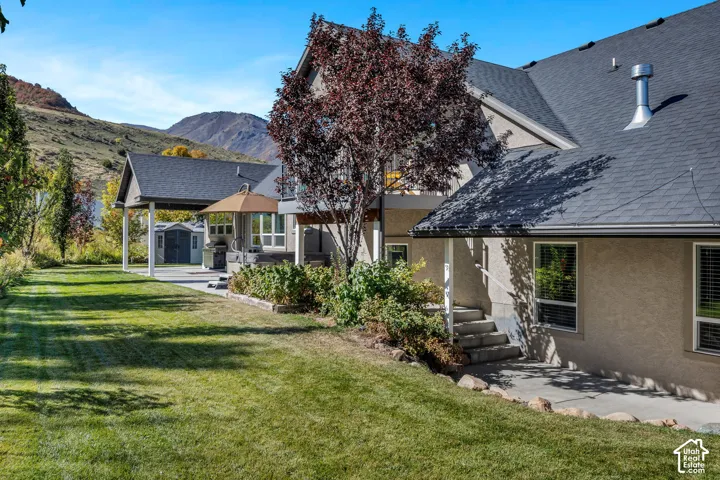 Expansive grassy yard with mature landscaping, a covered patio, and a separate paved patio area