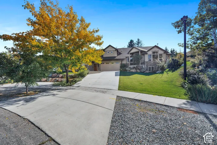 Multi-level residence featuring stone and stucco exterior, an attached two-car garage, and a concrete driveway