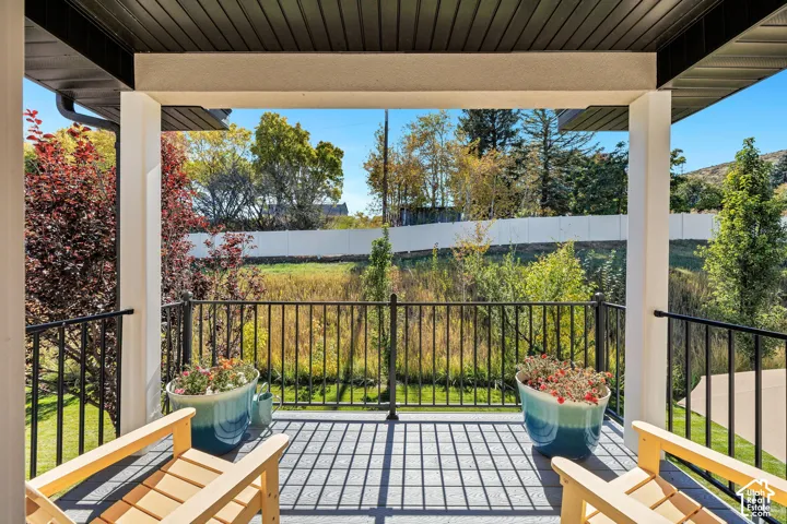 Covered outdoor deck with composite decking, white columns, and black metal railings