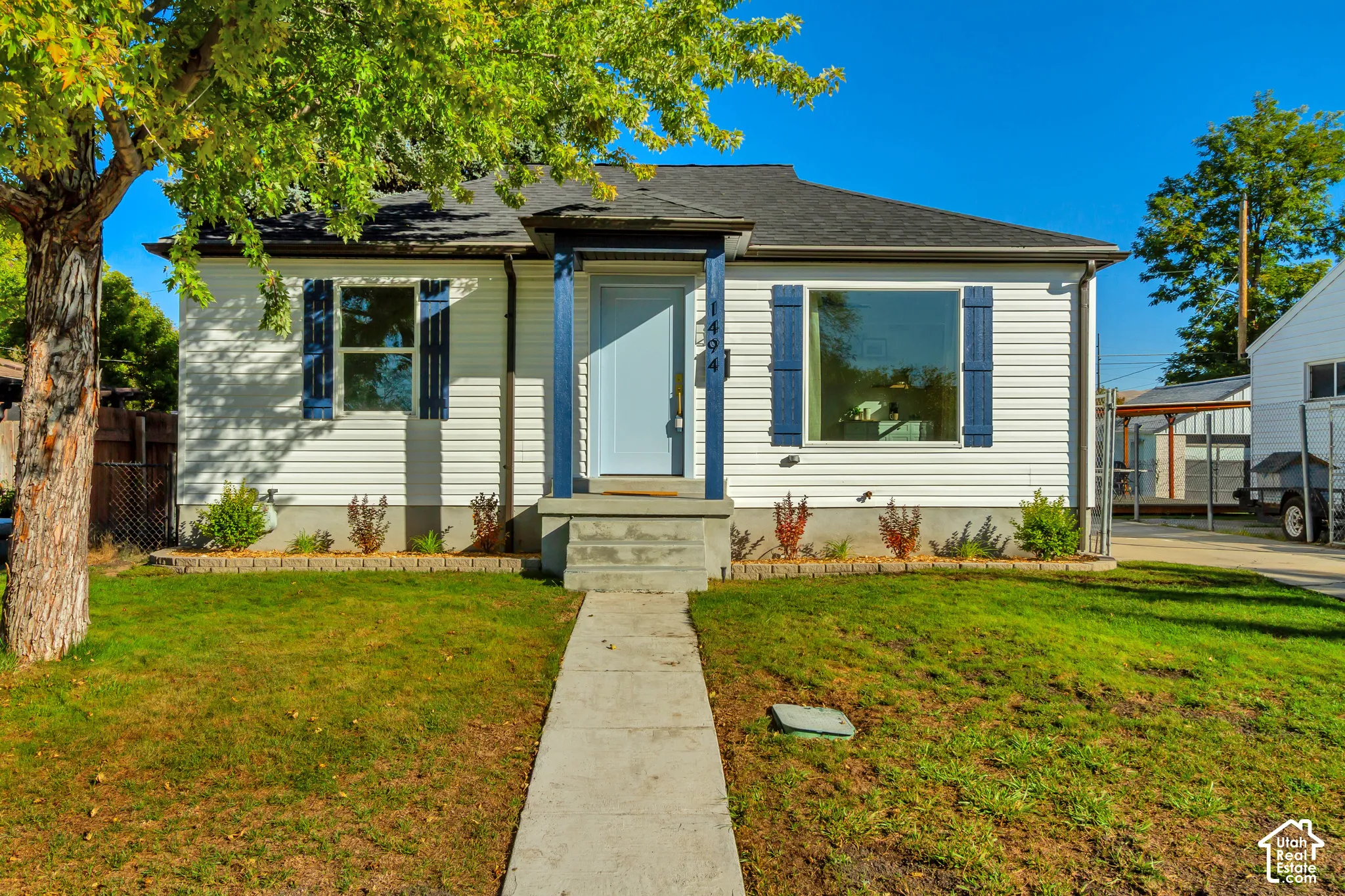 White horizontal siding exterior with contrasting blue shutters, a blue front door, and a dark shingle roof