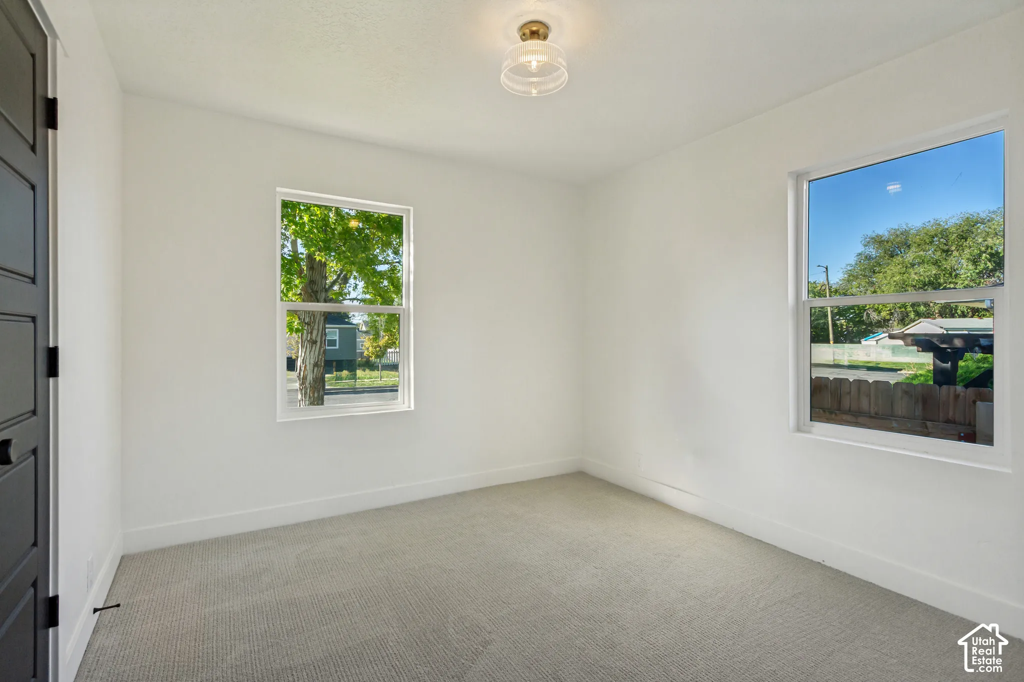 White walls with a light-colored carpet, two windows, and a flush-mount ceiling light fixture