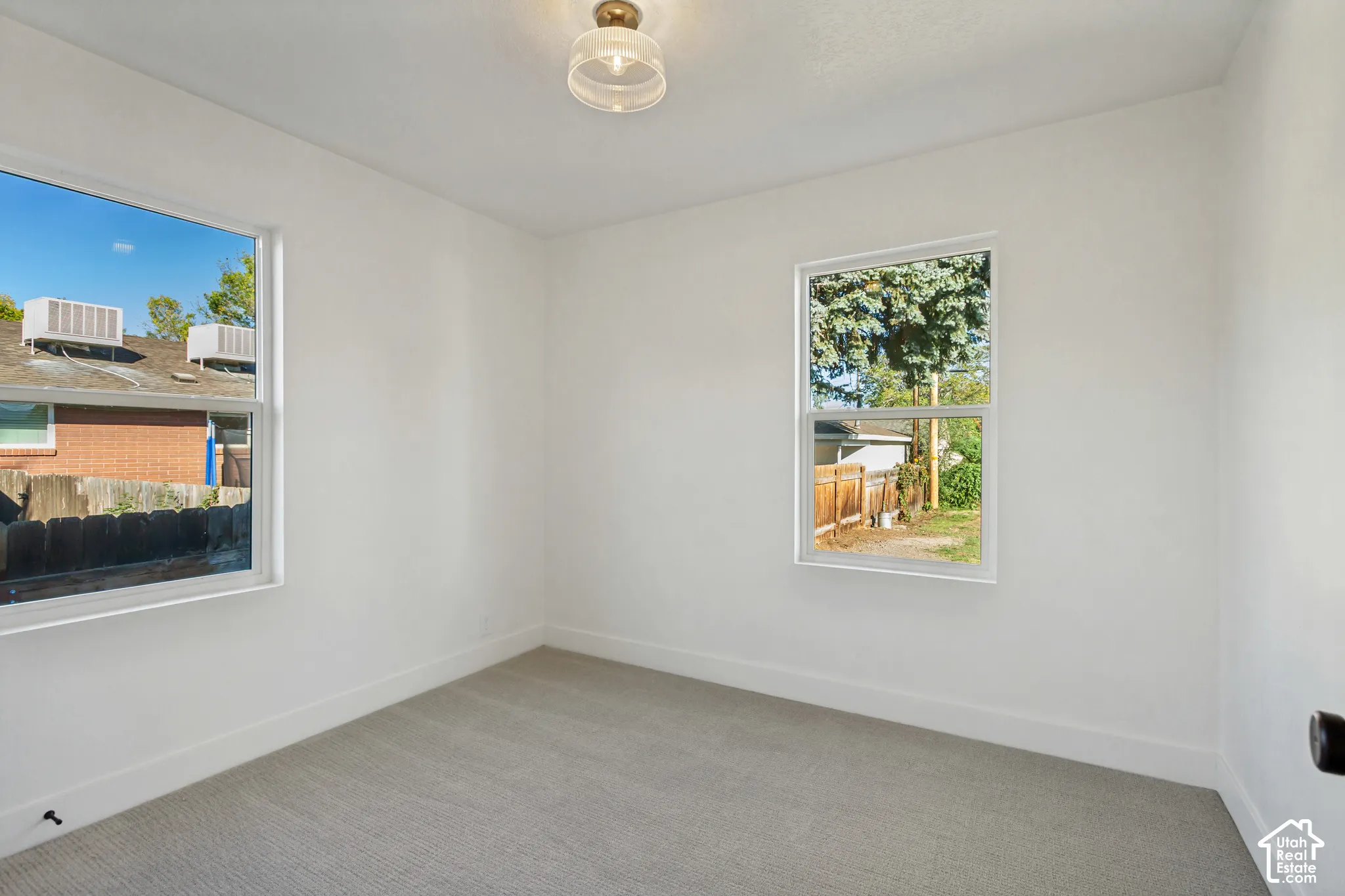 Crisp white walls, two windows, and a flush mount ceiling fixture
