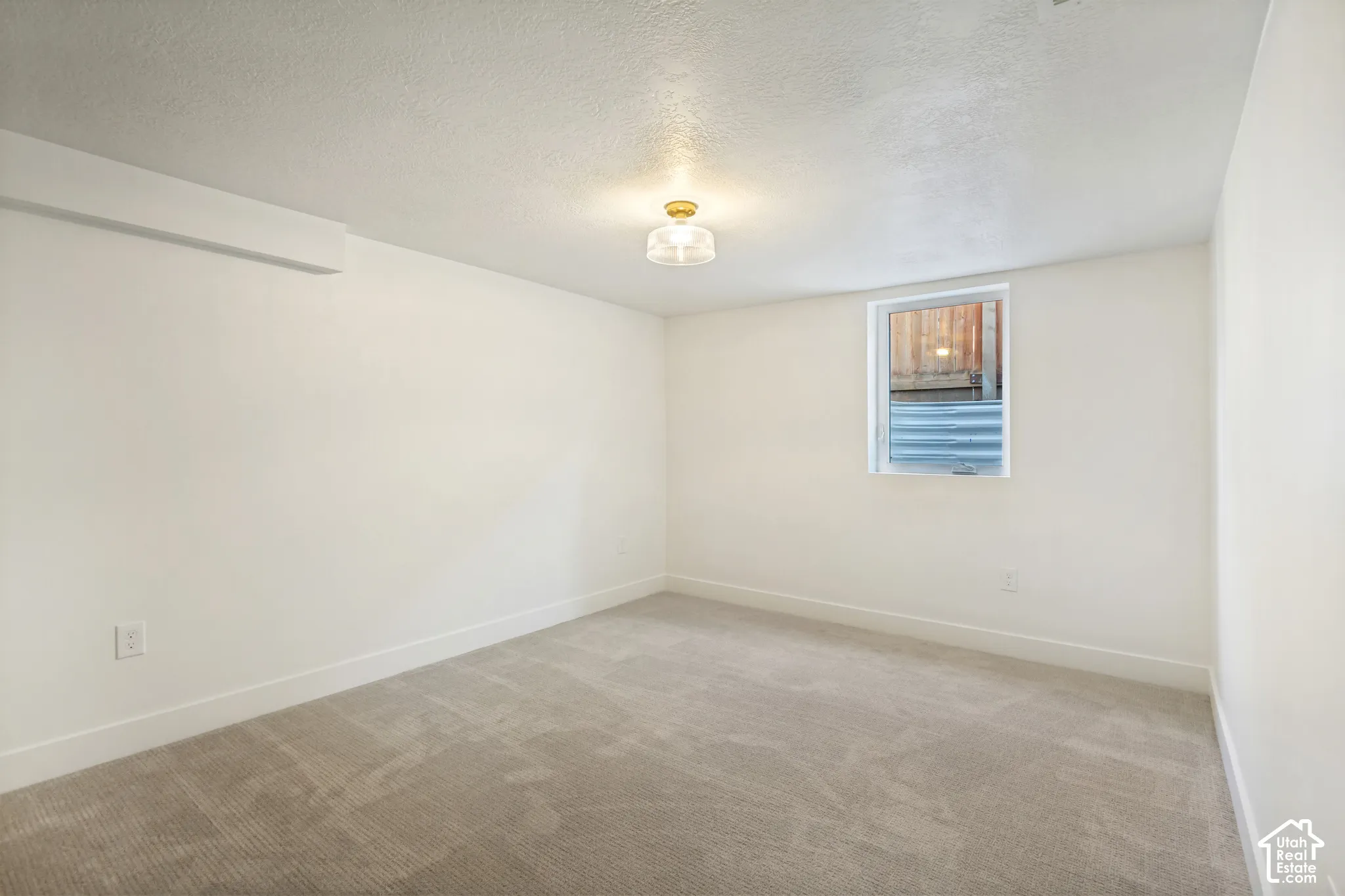 Recessed ceiling light, neutral carpeting, white wall finishes, and a single window