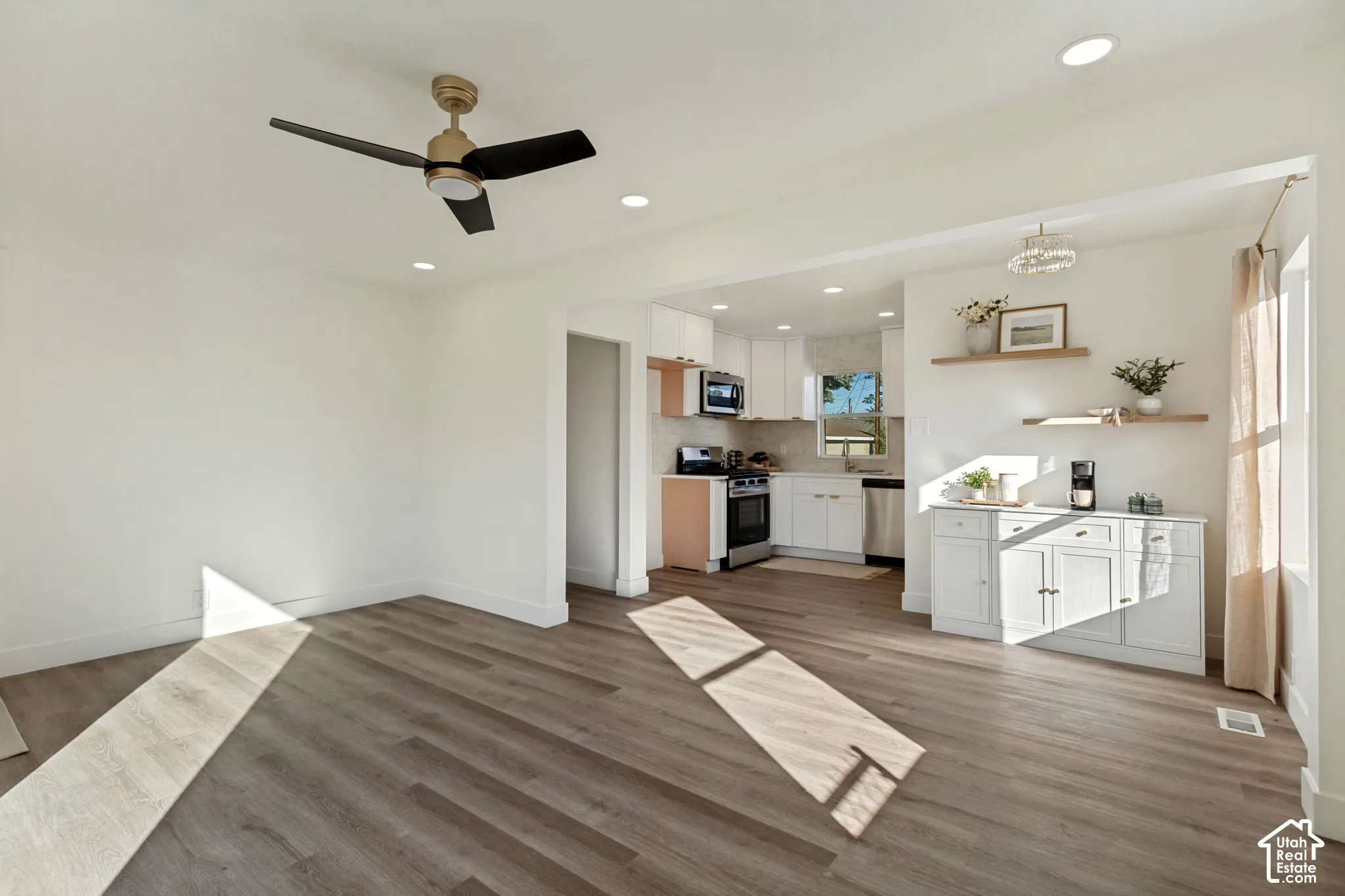 Expansive room with wood-finish flooring, recessed lighting, and a ceiling fan