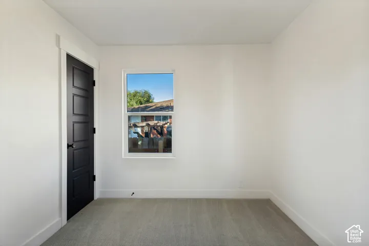 Neutral wall color, carpeted flooring, black paneled door, white trim, and a window