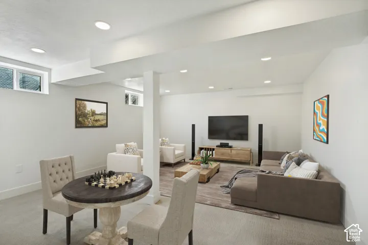 Recessed lighting illuminates this bright, open space featuring carpeted flooring and white painted walls