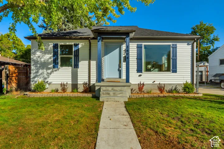 White siding exterior with a dark shingle roof, blue decorative shutters, and a light blue entry door