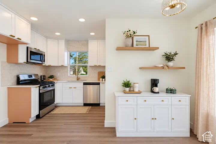 Kitchen featuring white cabinetry, stainless steel appliances, a tile backsplash, and wood-finish flooring