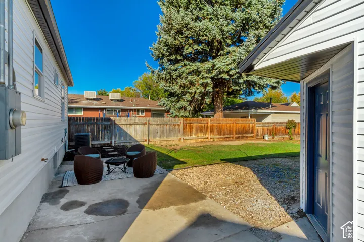 Concrete patio area, wood fencing, mature trees, and a grass lawn