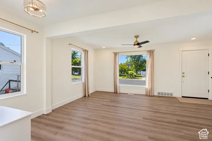 Spacious room featuring wood-finish flooring, recessed lighting, and a modern ceiling fan