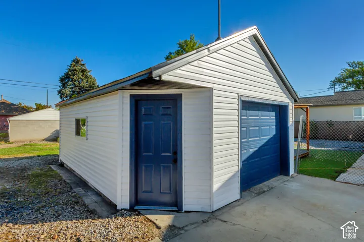 Detached garage with white siding, blue pedestrian door, and blue garage door