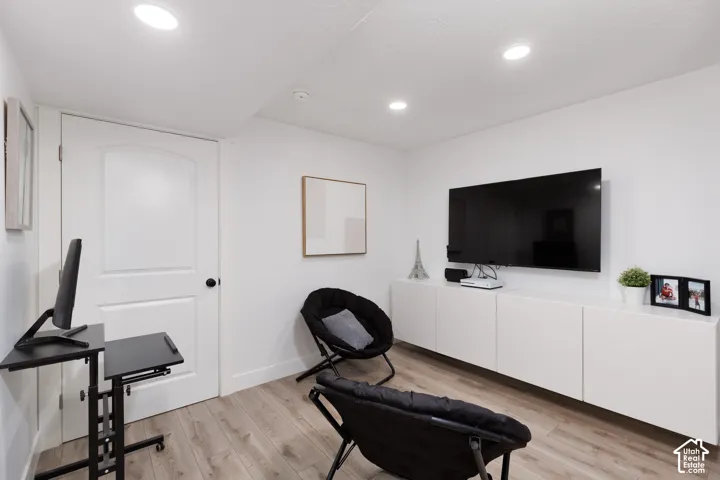Recessed lighting illuminating the room, featuring wood-finish flooring and white walls