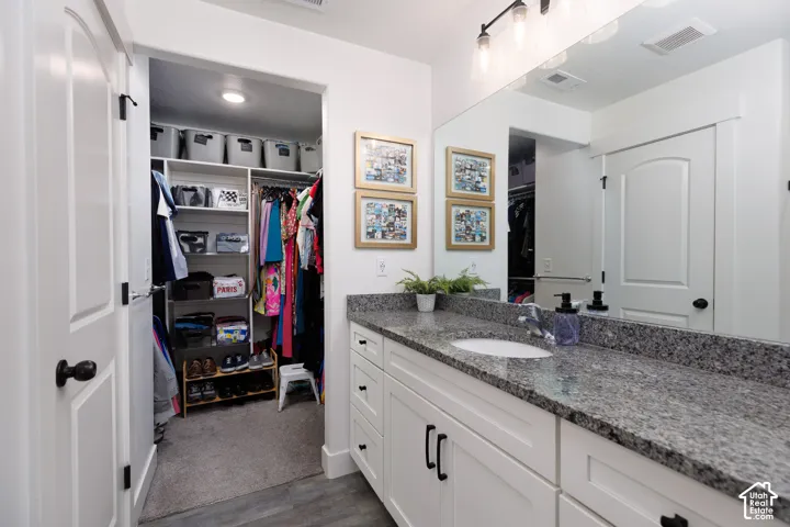Vanity with a white undermount sink, speckled countertop, and white cabinetry with black hardware