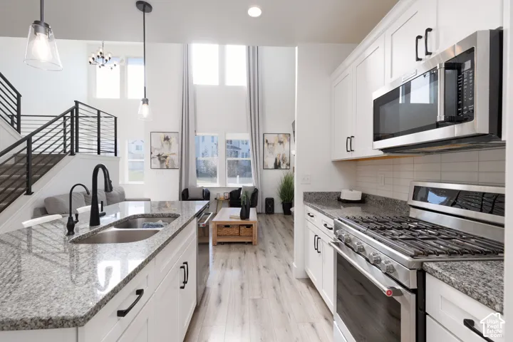 Kitchen featuring white cabinetry with black hardware, stainless steel appliances, granite countertops, and a white subway tile backsplash