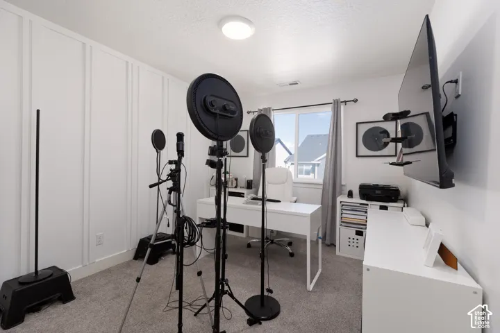Board and batten accent wall, recessed lighting, double-pane window, wall-mounted television, and neutral carpeting